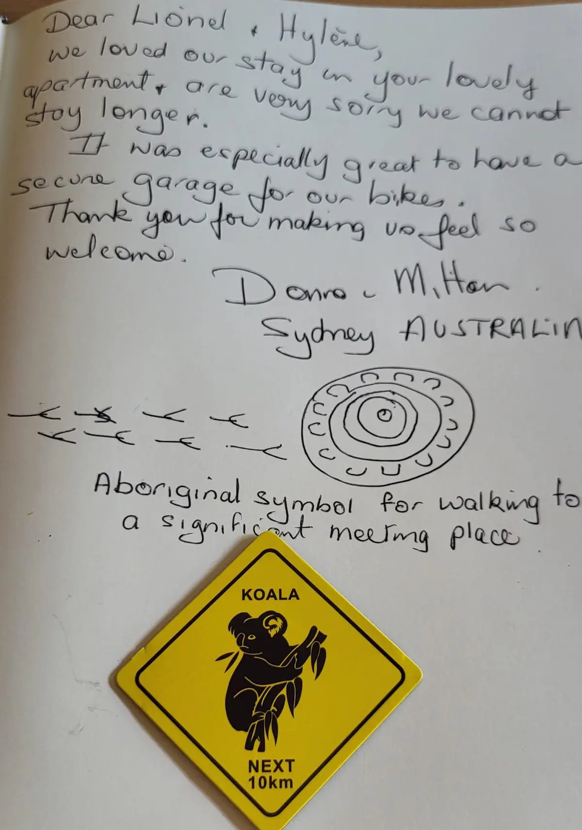 Page du livre d'or : message manuscrit de Donna, venue de Sydney, qui remercie pour le garage sécurisé pour les vélos, avec un symbole aborigène dessiné et un magnet koala